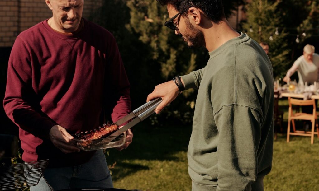 Twee mensen grillen een stuk vlees op de barbecue
