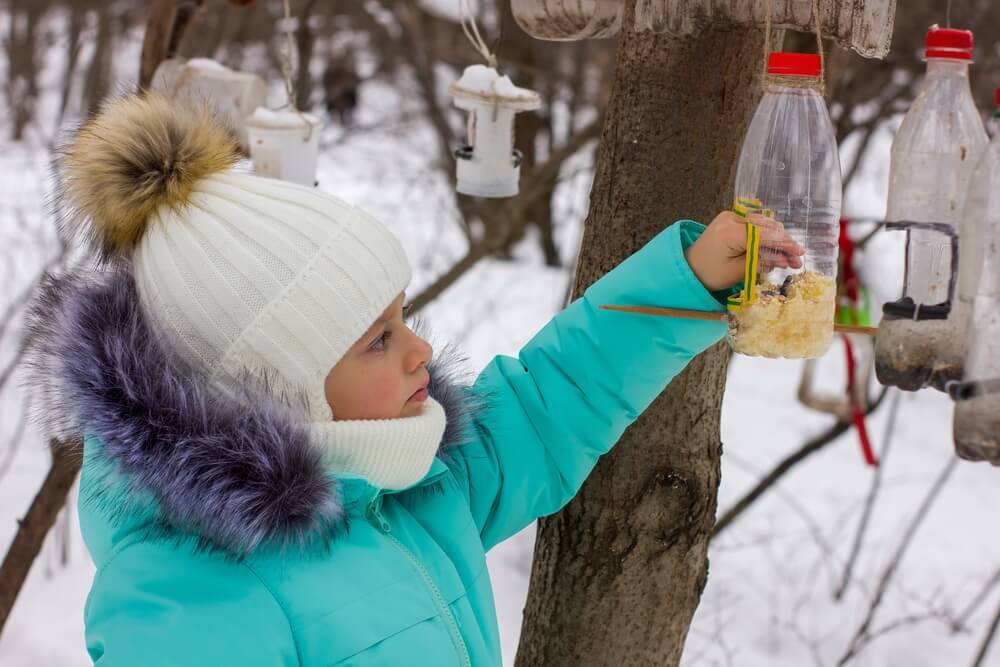 Kind controleert voedselstations voor vogels