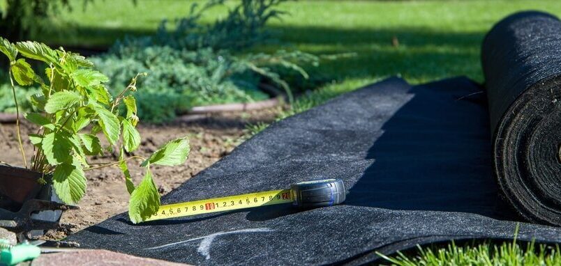 Worteldoek en meetlint op tuinbodem
